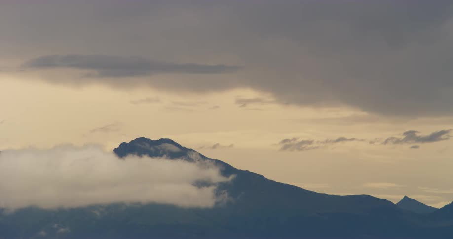 A very slow motion shot of clouds moving past a mountain