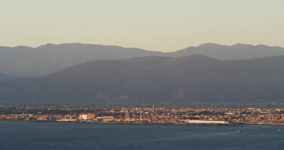 Aerial view of the silhouette of a mountain range behind a waterfront city near the coast