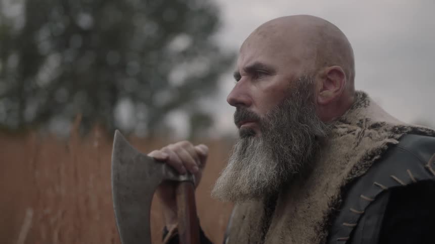 A man looks up leaning on an axe