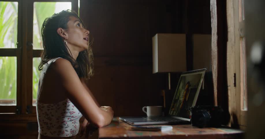 Young happy woman sitting at a desk at home talks on a video call on a laptop