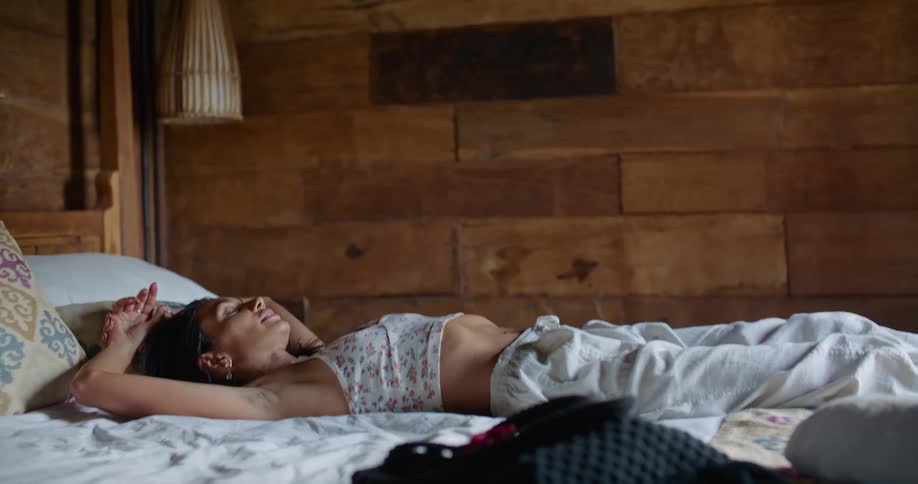 Woman lays backwards onto a bed