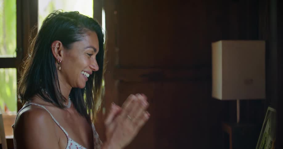 Woman with straight hair earrings printed halter blouse and tattoo makes video call on laptop waving at man