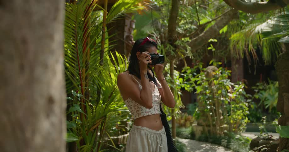 Woman stands on path in lush garden and takes pictures