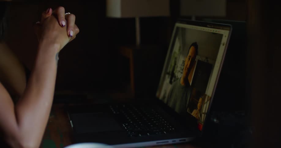 Woman with straight hair earrings printed halter blouse and tattoo makes video call on laptop