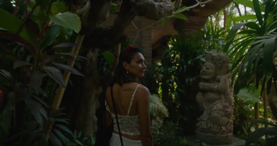 A woman is walking through a garden of a temple