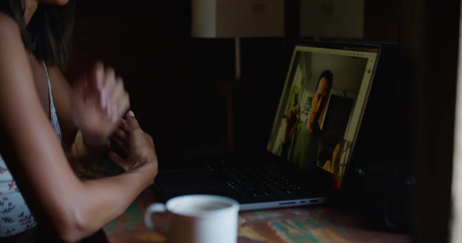 Young happy woman sitting at a desk at home talks on a video call on a laptop