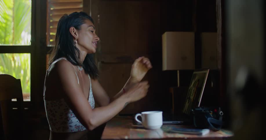 Woman sitting at the desk having a video call with a friend on her laptop