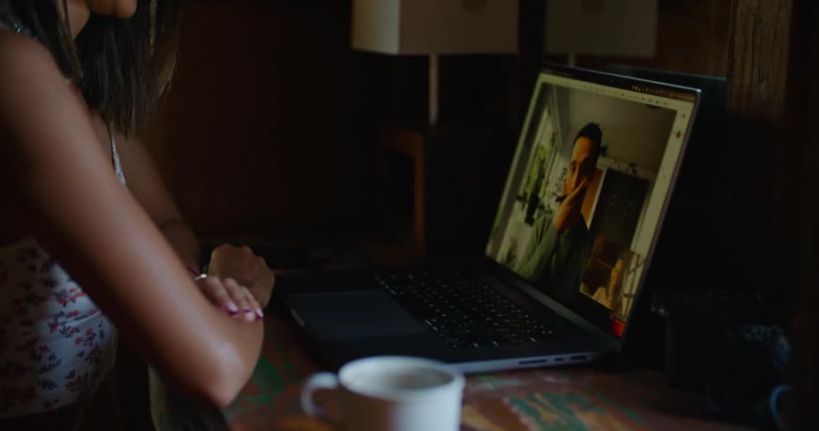 Young happy woman sitting at a desk at home talks on a video call through a laptop