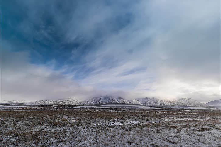 Clouds roll over the landscape to the mountains as snowy weather begins