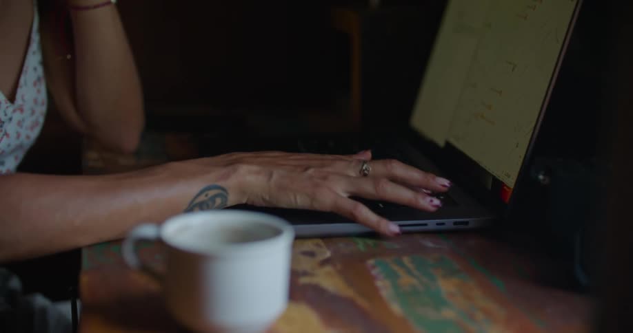 Young happy woman sitting at a desk at home typing on a laptop