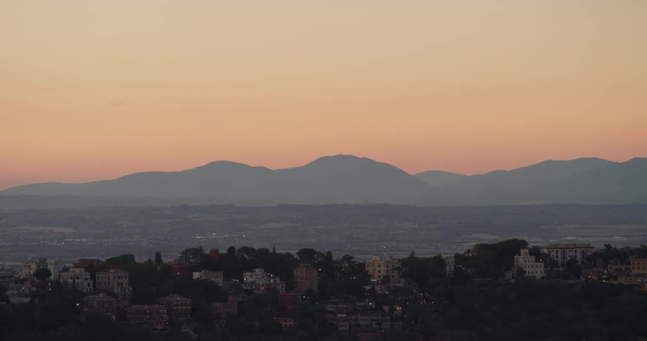 Silhouette of a mountain behind a small city at evening