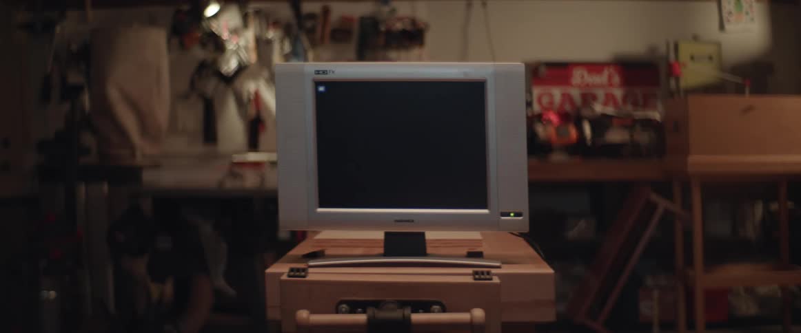 A television is on a table with a dark screen and the green button flashes and text appears on a corner of the screen