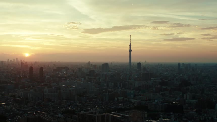 Sun sits near horizon in red sky as city stretches in all directions around tall tower