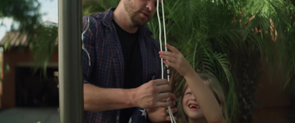 Father helps daughter to rise a flag on the flagpole in the backyard at morning