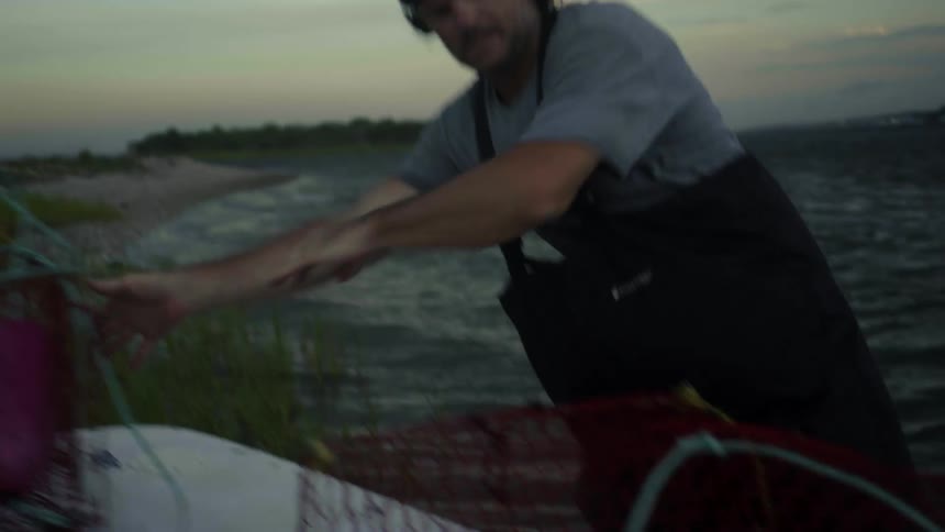 A fisherman moves nets around on his boat