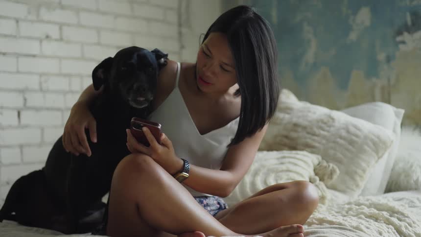A woman uses her smartphone to take a selfie with her dog
