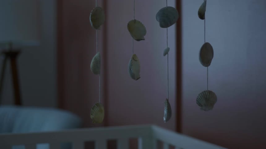 Mobile of shells swings over crib in baby room