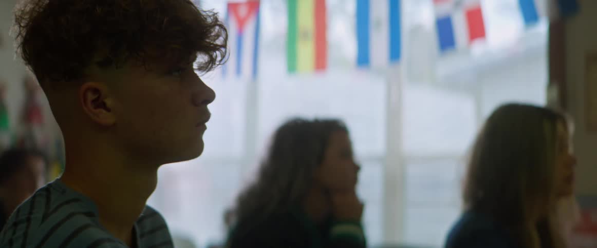 Students listen while sitting at their desks in a classroom