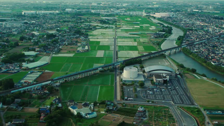 Train travels over streets and across a river toward the city center