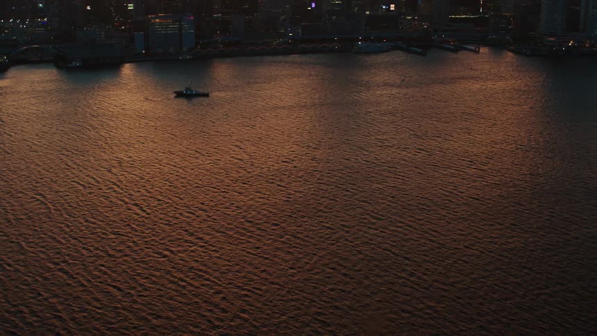 Aerial view of tall skyscrapers on the skyline of a waterfront city at evening