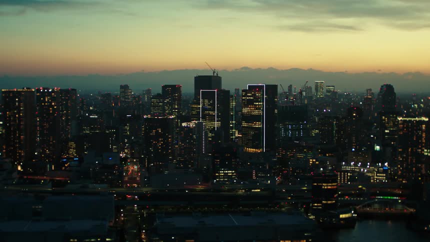 An aerial view of city skyscrapers and lights at dawn