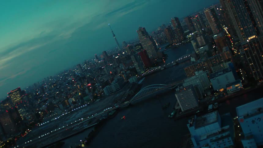 An aerial view of a river running through a city with high rise office buildings and vehicles driving