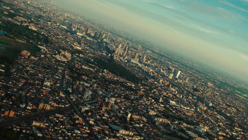 Skyscrapers and towers stand tall above a crowded metropolitan city under a cloudy sky