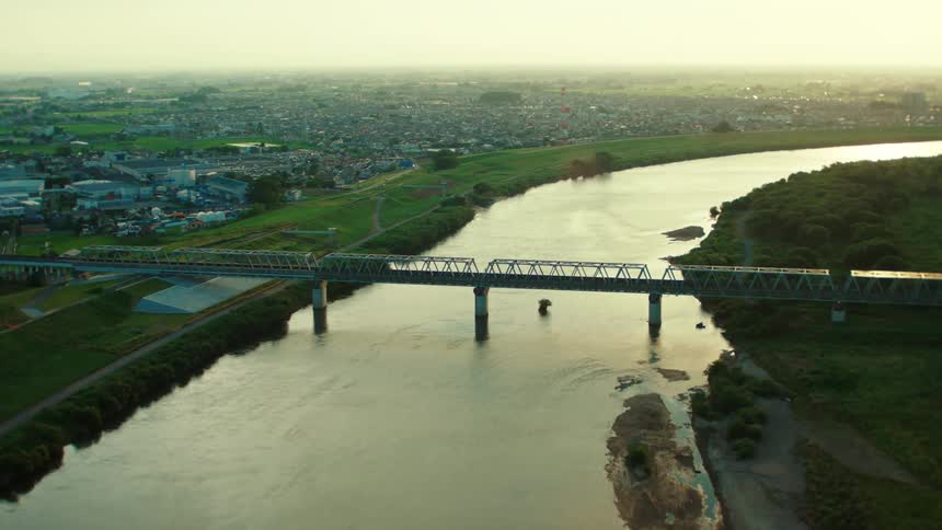 Roads parallel river on either side of bridge where one side is urban and the other is woods