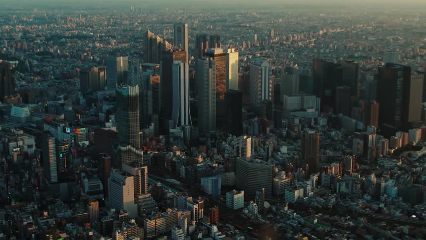 Skyscrapers and towers stand tall above a crowded metropolitan city under a hazy sky
