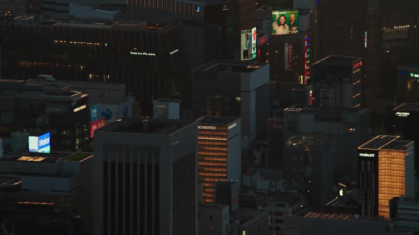 Large outdoor screens display images on skyscrapers in downtown on foggy evening