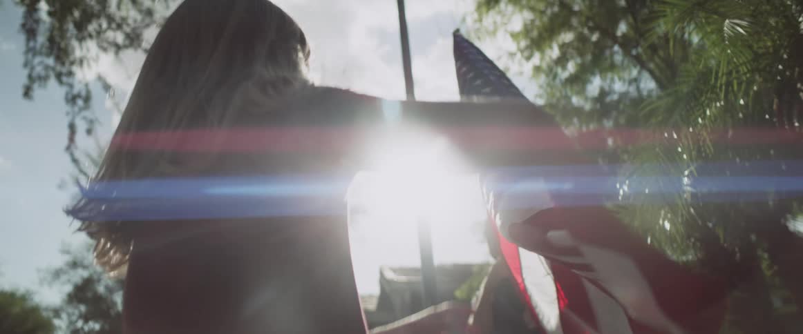 A young girl holds and admires an american flag