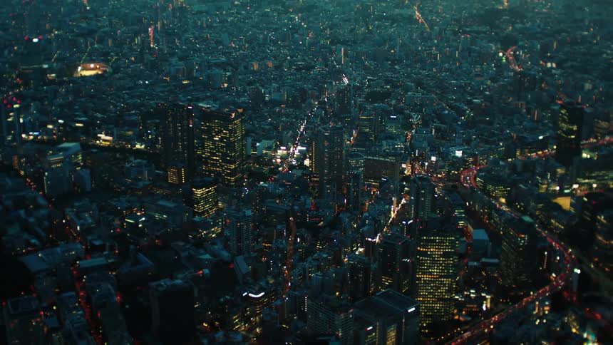 An aerial view of buildings in a city skyline with vehicles driving on roads