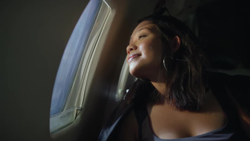 A woman looks out the plane window