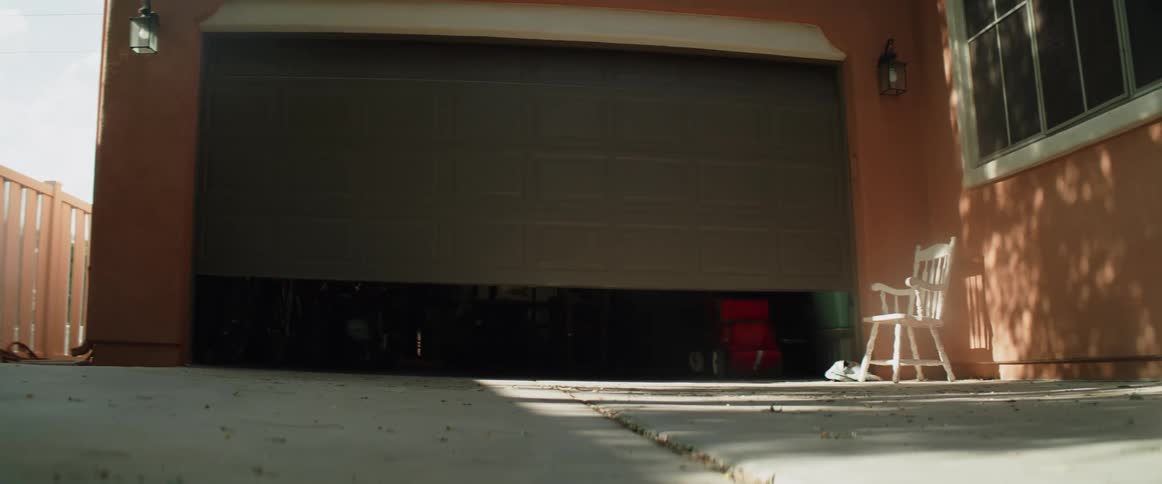 A garage door lifts up and a little girl runs under the door and down the driveway with a smile on her face