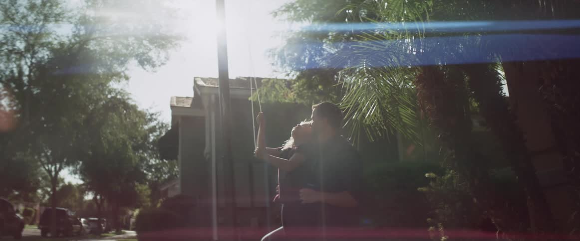 Man and daughter raise flag on flagpole on a sunny