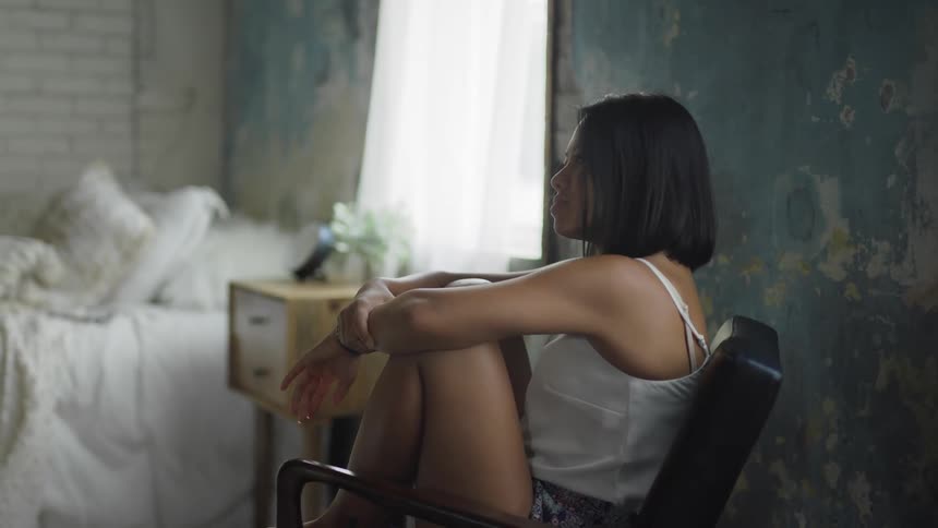 A woman sits down in her bedroom