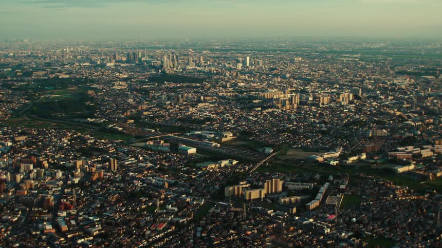 Urban sprawl occupies both sides of river under an overcast sky on a hazy day