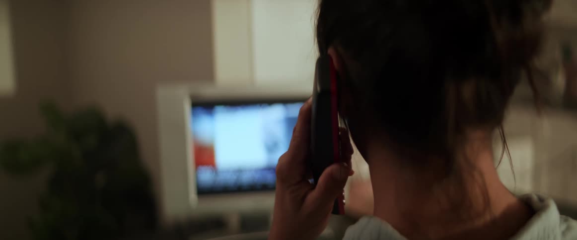 Woman calls on smartphone while watching news broadcast