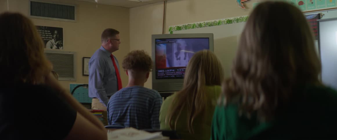 A teacher plays video for his students in a high school classroom