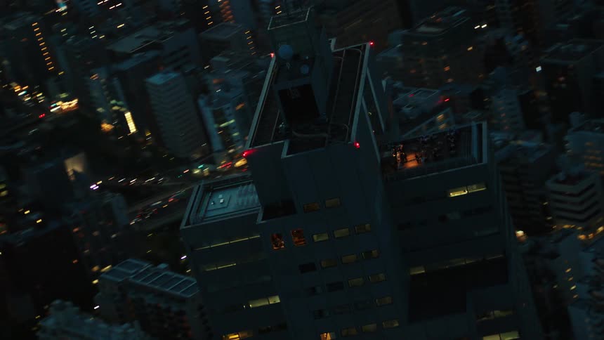 Aerial twisting view of a tall skyscraper on the city skyline at night