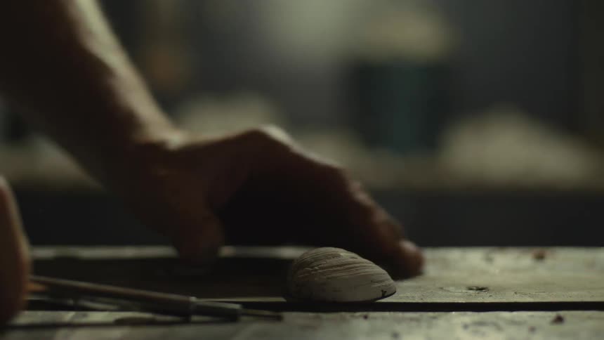 A man using a tool on a clam almost causes an accident that could hurt himself