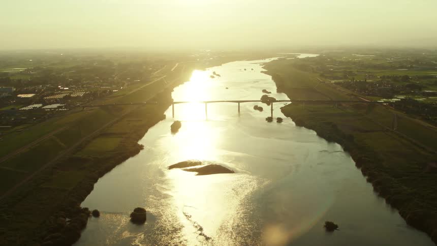 Light glints off of river dividing large town on a hazy day