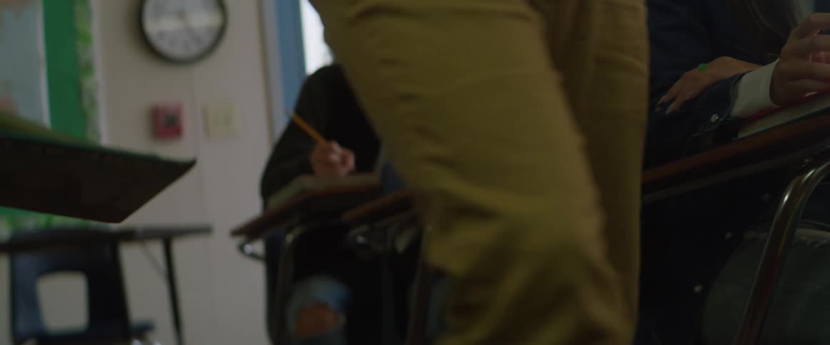 Students pass each other a note before a teacher walks by in a classroom