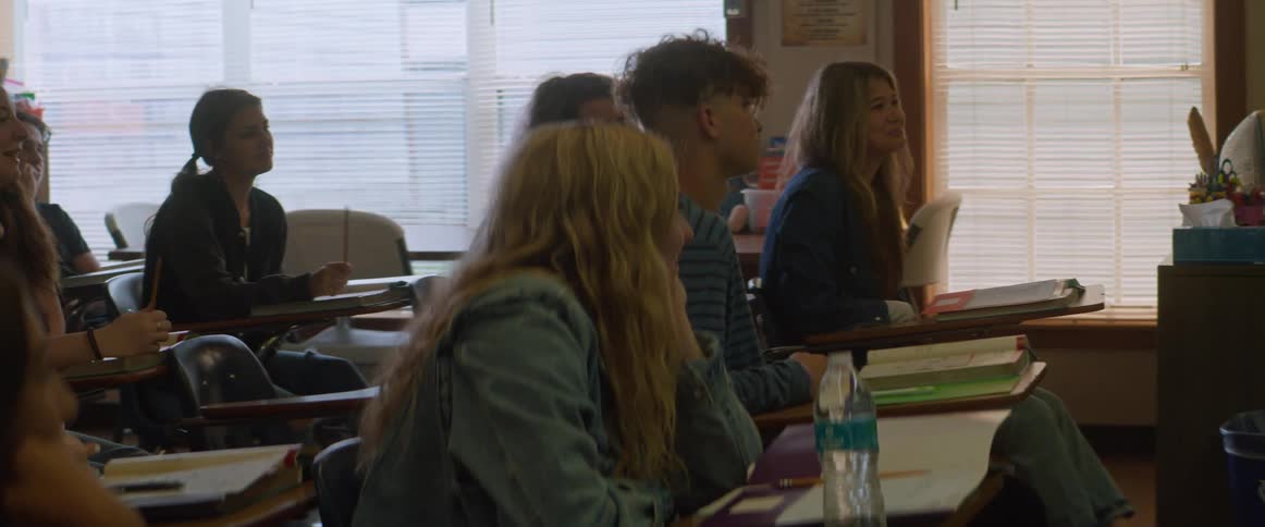A group of happy relaxed students sitting on a classroom listening to a professor