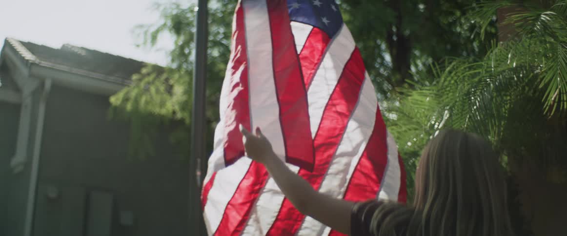 Father and daughter rising the american flag on the backyard in the morning