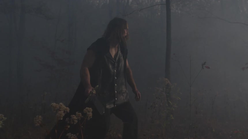 A man carrying a sword moves in a forest