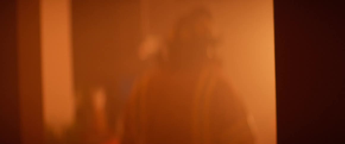 A firefighter walks into another room that is on fire