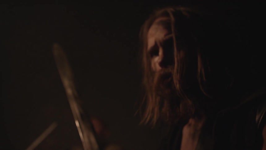 A man holds a sword and looks around at night