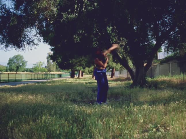 A woman is dancing outdoors at a park in spring