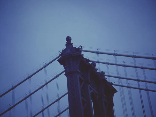 Silhouette of a person walking across the top of a suspension bridge